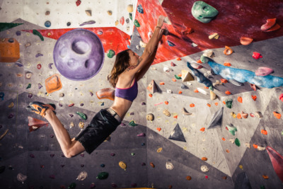 young woman climbing artificial boulder indoors Eine Frau beim bouldern.