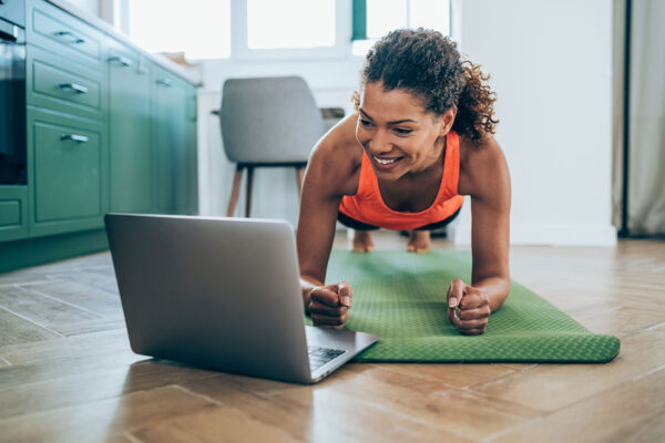 Eine Frau macht ein Workout zuhause über ihren Laptop