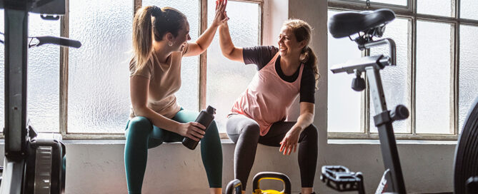 Zwei Frauen beim Gewichtstraining geben sich High Five.