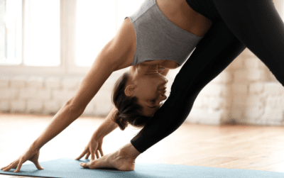 Eine Frau macht auf einer Matte Yoga und dehnt ihr Bein