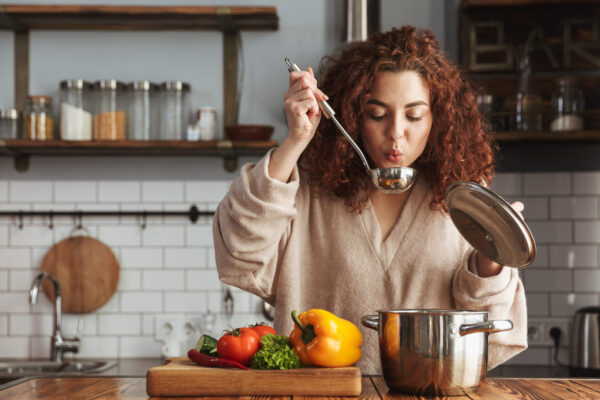 Eine Frau probiert mit einem Löffel ihre Suppe