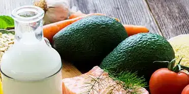 Avocado, Milch, Tomate und Karotten liegen auf einem Tisch