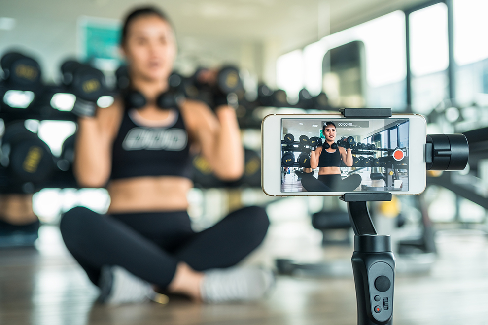 Frau erklärt online Fitness mit einem Smartphone. Frau mit einem Smartphone