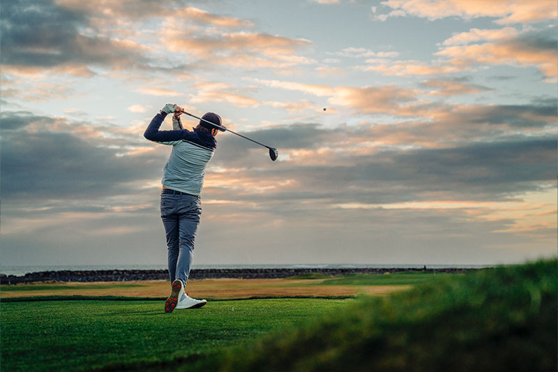 Eine Person auf einem Golfplatz schlägt den Ball