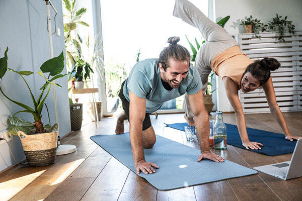 hansefit_krankenkassen_anfrage Ein Mann und eine Frau machen gemeinsam zuhause Sport auf Yogamatten
