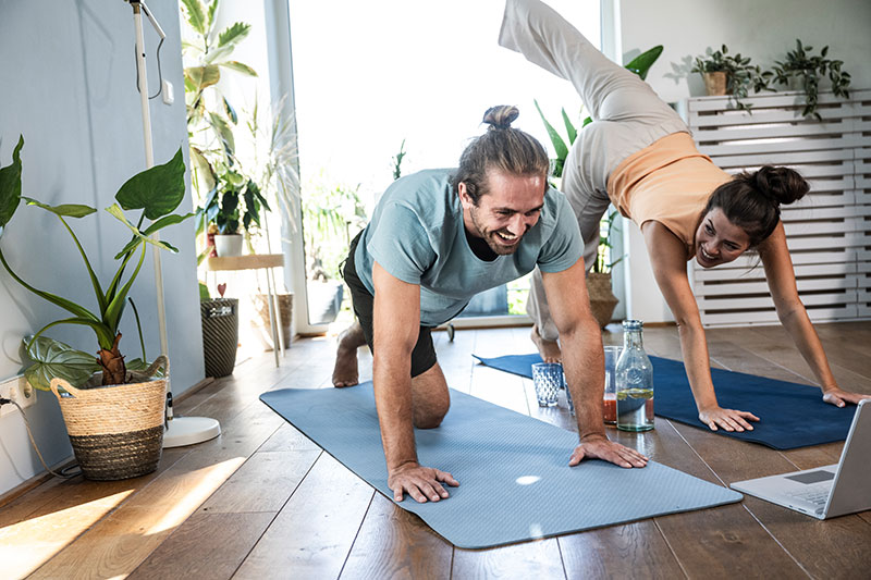 hansefit_krankenkassen_anfrage Ein Mann und eine Frau machen gemeinsam zuhause Sport auf Yogamatten