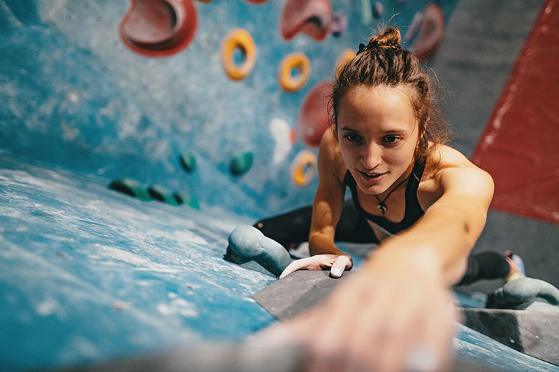 Eine Frau erklimmt eine Wand beim bouldern