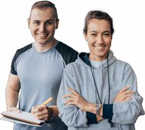 Ein Trainer und eine Trainerin schauen freundlich, der Trainer macht Notizen