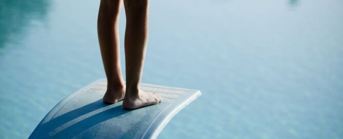Eine Person steht auf einem Sprungbrett im Freibad.