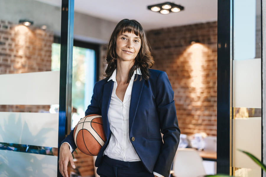 Eine Frau steht in einem Büro und hat einen Baseball zwischen Arm und Hüfte.