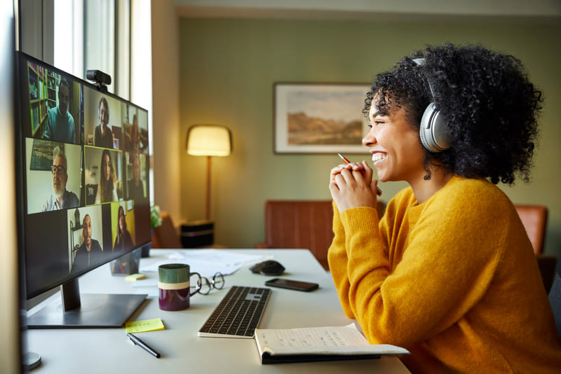 Eine Frau sitzt mit Headset vor dem PC