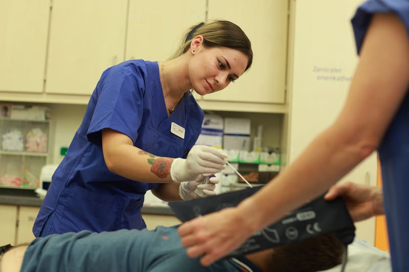 Eine Mitarbeiterin von der Helios Klinik behandelt eine Person.