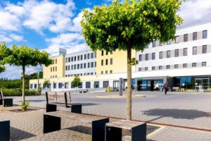 Die Helios Klinik von Außen mit Bäumen und einer großen Anlage.