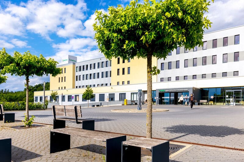Die Helios Klinik von Außen mit Bäumen und einer großen Anlage.