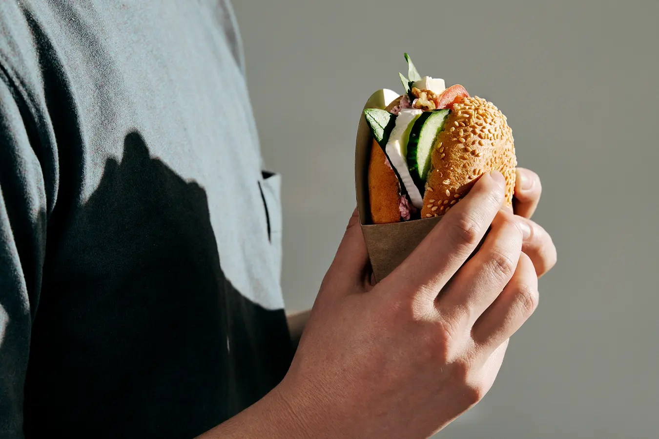 Eine Person hat einen Bagel in der Hand.